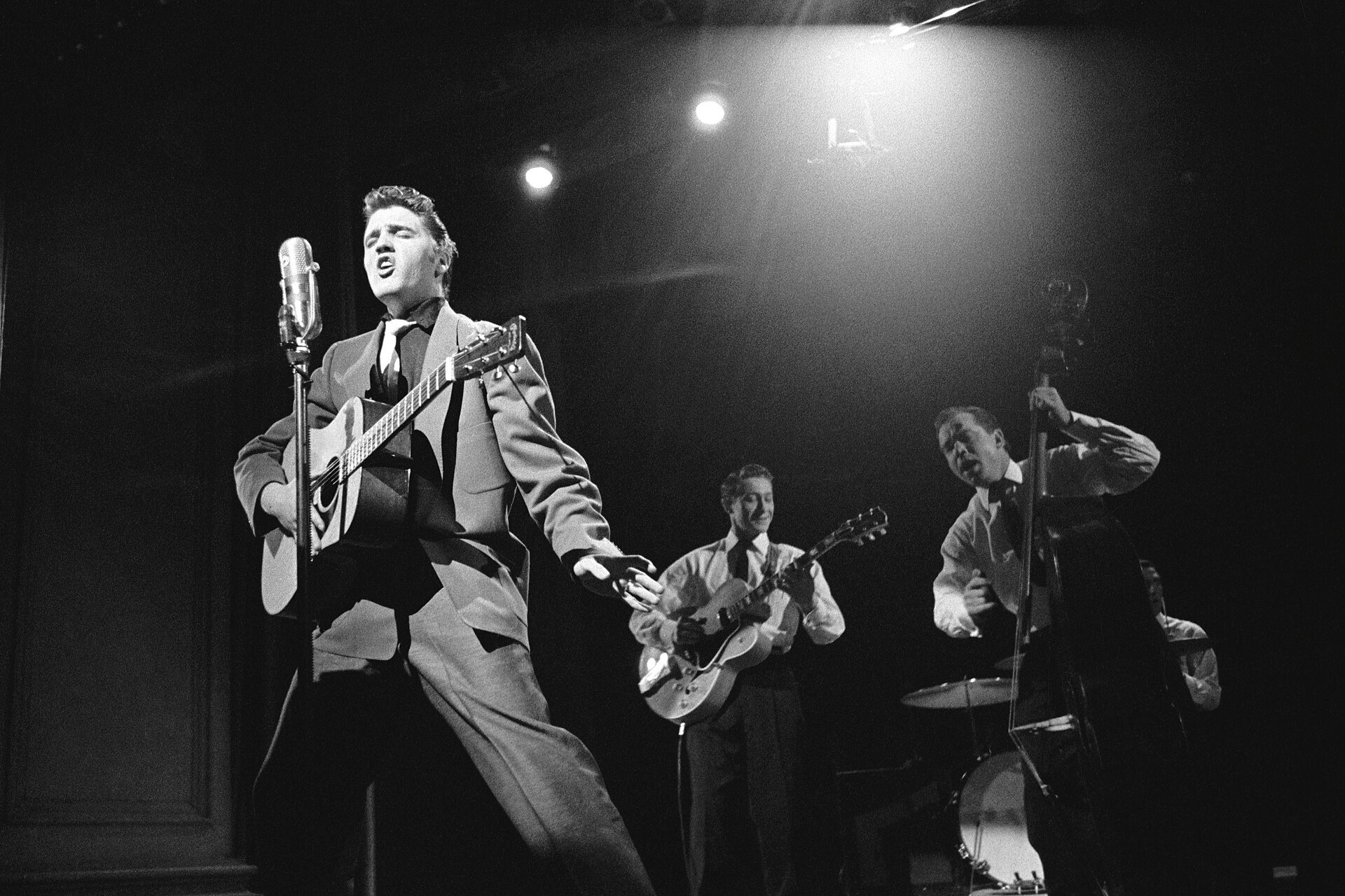 Elvis Presley on stage in 1956 with Scotty Moore on guitar and Bill Black on bass